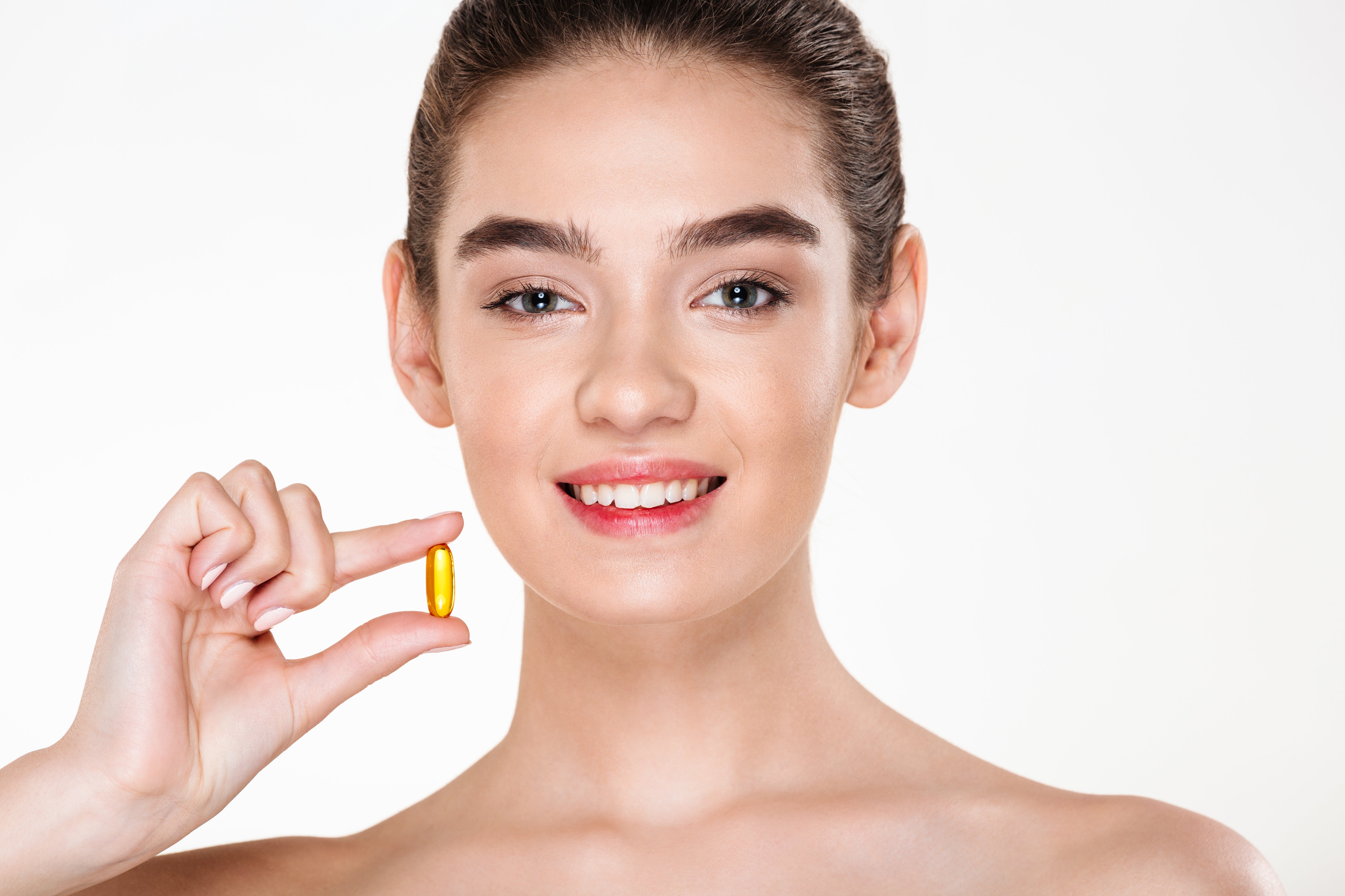 beauty-portrait-of-smiling-healthy-woman-with-dark-hair-holding-capsule-meds-or-vitamin-in-her-hand-posing